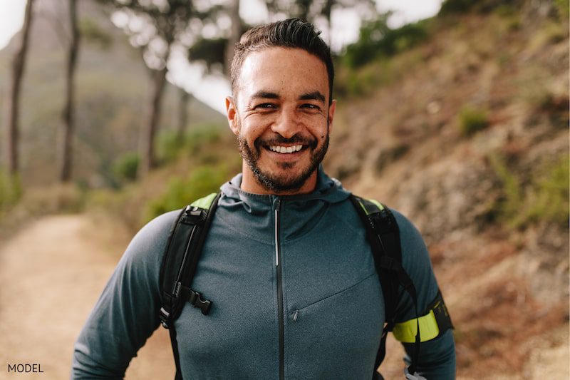 Happy man with a backpack smiling on a hike.