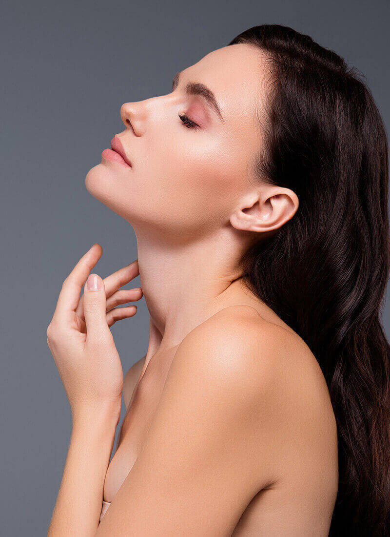 side profile of a shirtless woman rubbing her firm and thin neck